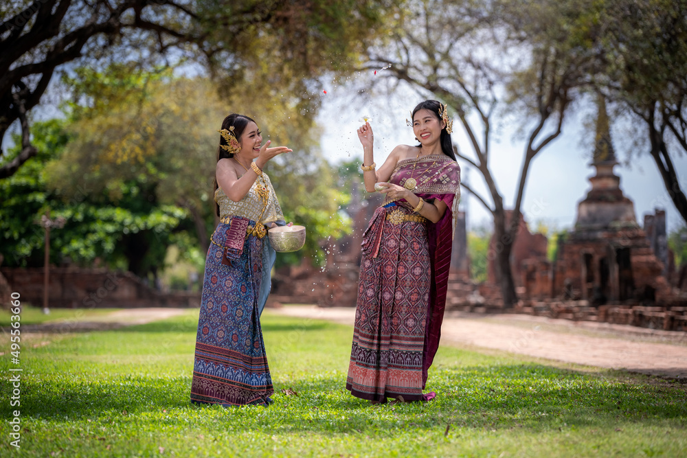 Beautiful Asian woman wearing Thai dress traditional pose happiness to playing splash water during Songkran festival is funny festival traditional holiday in Thailand .