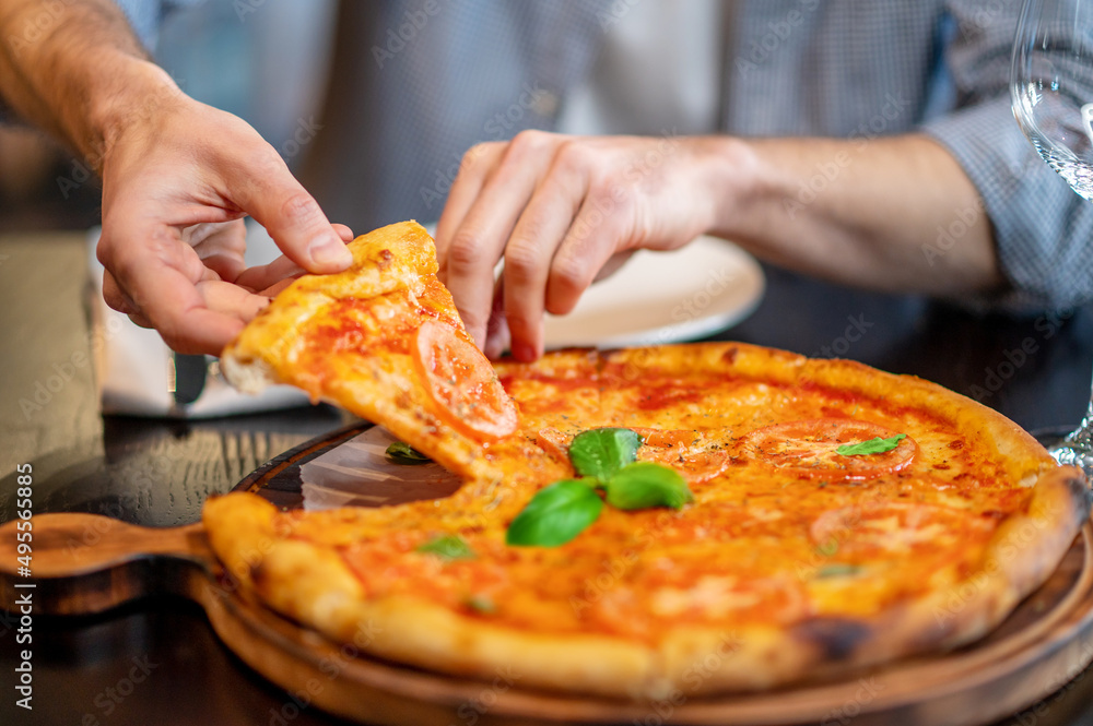 Close up picture of mans hands taking a slice of pizza