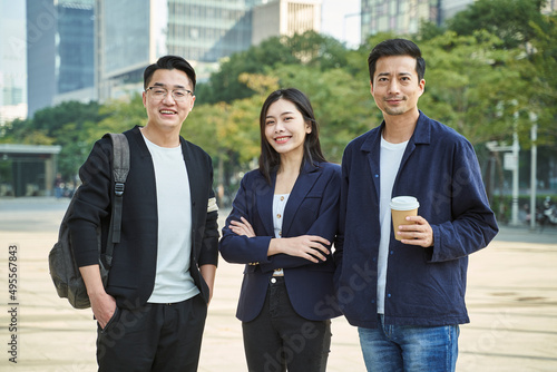 outdoor portrait of three young asian people in casual wear looking at camera smiling