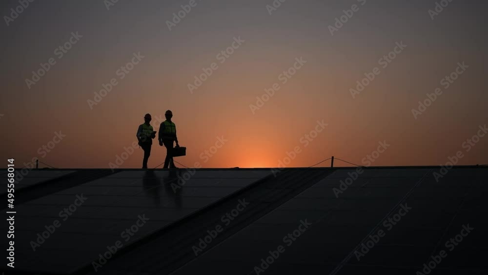Engineers walking on roof inspect and check solar cell panel by hold equipment box and radio communication ,solar cell is smart grid ecology energy sunlight alternative power factory concept Engineers walking on roof inspect and check solar cell panel by hold equipment box and radio communication ,solar cell is smart grid ecology energy sunlight alternative power factory concept