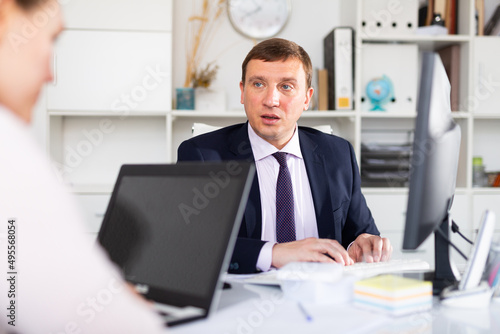 Focused adult successful man working with computer in modern office