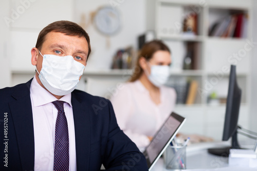 Portrait of adult businessman in protective medical mask at office