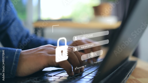 Fotografía A man's hand presses a laptop keyboard and a screen appears to enter username and password to login the system