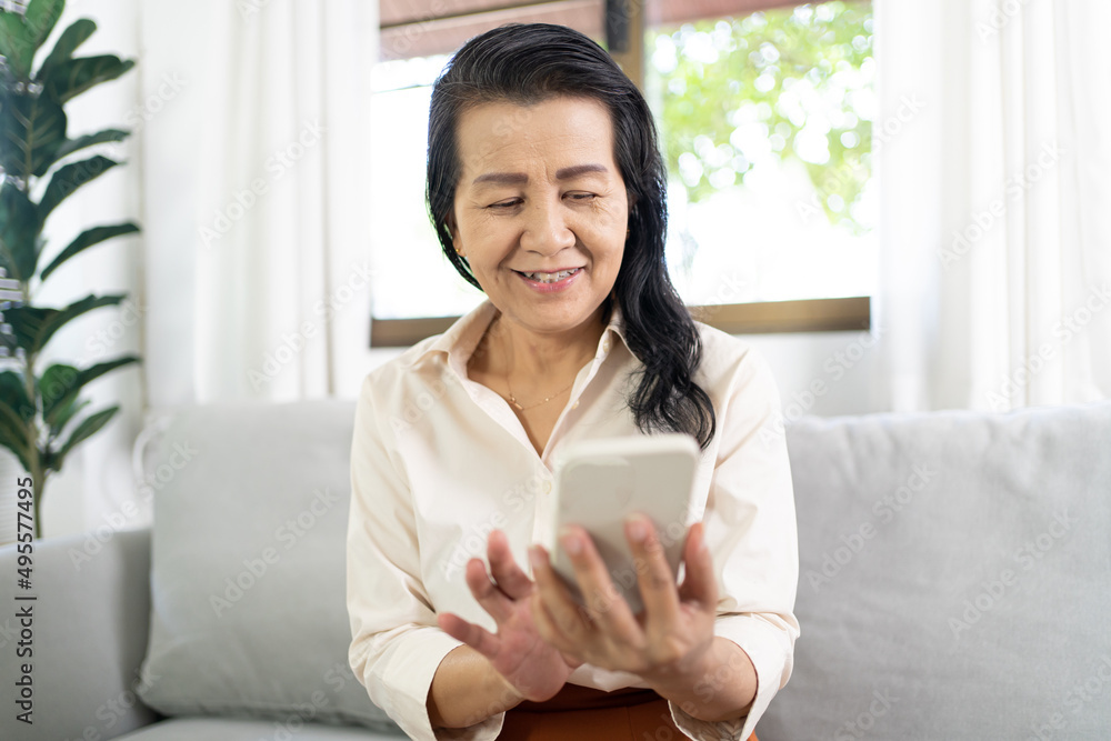 Middle age Asian woman holding cell telephone Work from home. smiling Beautiful mature asian woman VDO Call Conference smart phone with technology concept Middle age Asian woman holding cell telephone Work from home. smiling Beautiful mature asian woman VDO Call Conference smart phone with technology concept