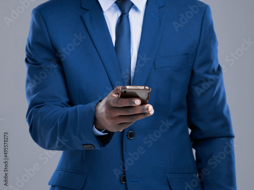 Let me make this call. Cropped shot of an unrecognizable businessman checking his text messages in studio against a grey background.