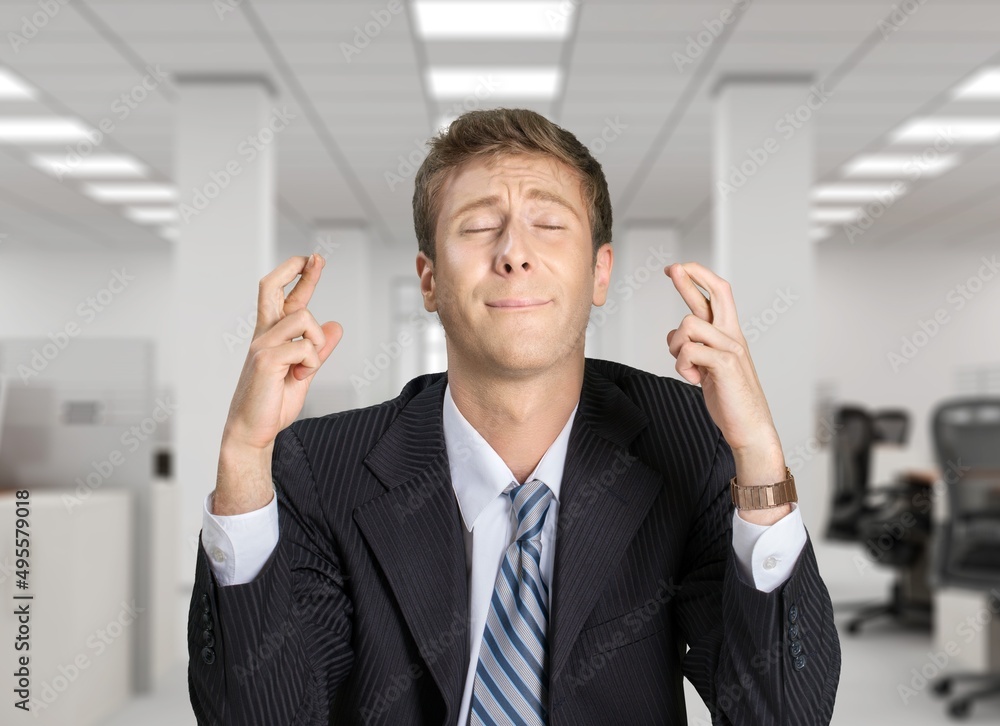 American young hopeful man in office with crossing fingers praying says prayer hopes for future possibility, hope faith concept. American young hopeful man in office with crossing fingers praying says prayer hopes for future possibility, hope faith concept.