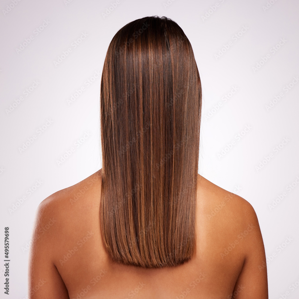Naklejka premium Perfectly layered. Studio shot of an unrecognizable young woman standing with her back facing the camera to show off her hair against a grey background.
