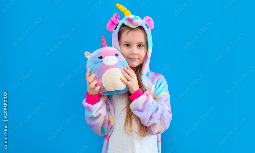 baby girl in a cozy blue unicorn costume poses in the studio on a blue isolated background. Place for text. baby girl in a cozy blue unicorn costume poses in the studio on a blue isolated background. Place for text.