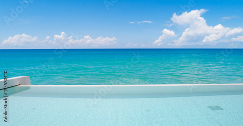 Swimming pool overlooking view tropical sea and clear blue sky background. Summer holiday and Travel background concept