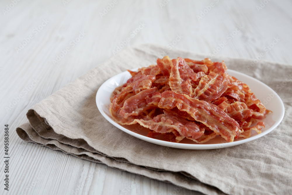 Crispy Fried Bacon on a white plate, side view. Space for text.