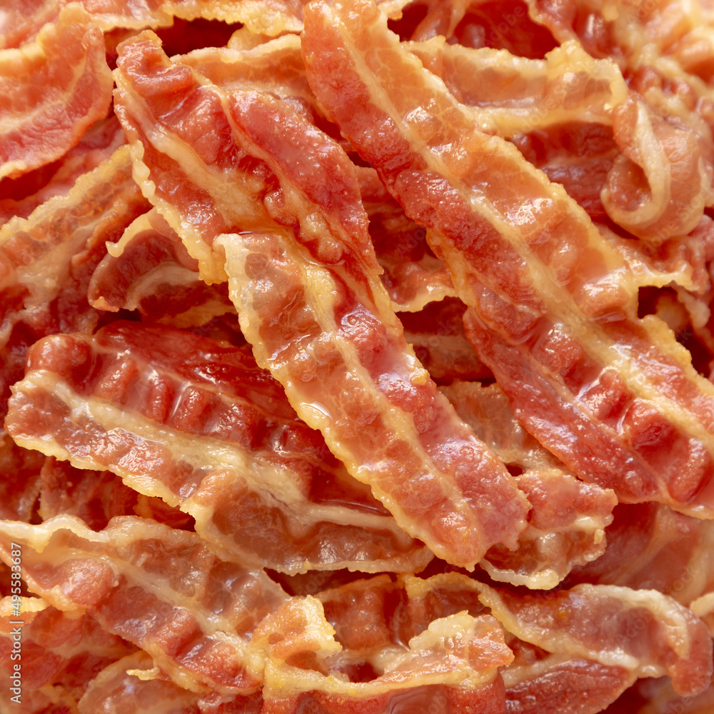 Crispy Fried Bacon on a white plate on a black background, top view. Flat lay, overhead, from above. Crispy Fried Bacon on a white plate on a black background, top view. Flat lay, overhead, from above.