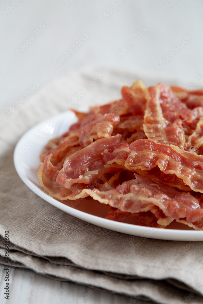 Crispy Fried Bacon on a white plate, low angle view. Close-up.
