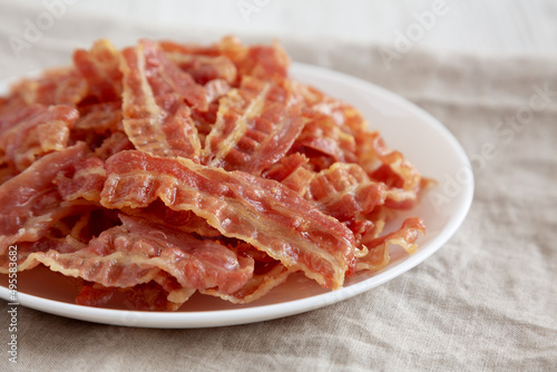 Crispy Fried Bacon on a white plate, side view. Close-up.