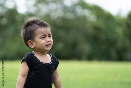 Asian little toddler boy is crying while he is walking alone in the park, concept of emotional expression of kid for scare, lonely, worry, upset, stress, depress in the childhood.