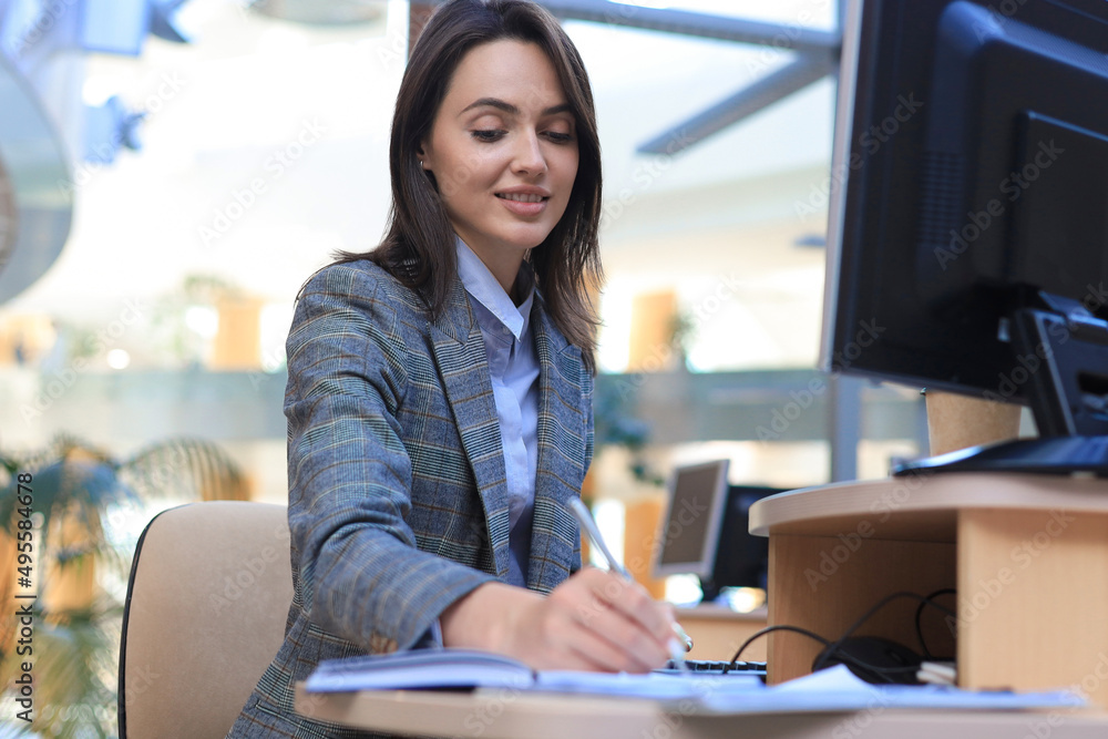 Beautiful business woman is examining documents while sitting in the office Beautiful business woman is examining documents while sitting in the office