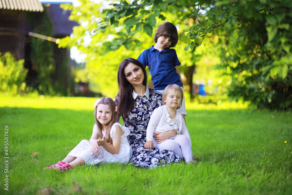 Young large family on a summer morning walk. Beautiful mother with children is playing in the park.