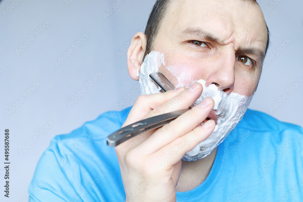 A man shaves in front a mirror. Shaving foam. Disposable razor. A man shaves in front a mirror. Shaving foam. Disposable razor.
