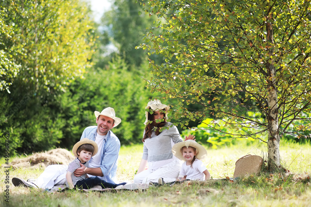 Happy family with children having picnic in park, parents with kids sitting on garden grass and eating watermelon outdoors Happy family with children having picnic in park, parents with kids sitting on garden grass and eating watermelon outdoors