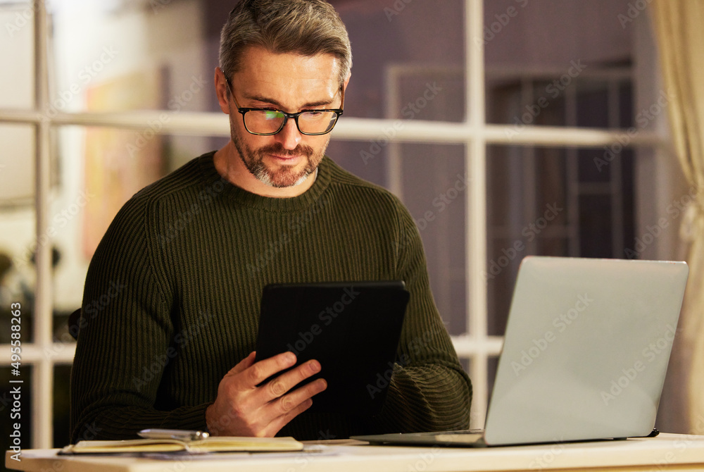 Determined to make his business a success. Cropped shot of a handsome mature businessman working on his laptop and tablet at home. Determined to make his business a success. Cropped shot of a handsome mature businessman working on his laptop and tablet at home.