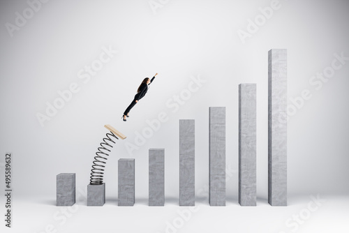 Concept of business boost and growth. Superhero businesswoman flying off of springboard to business chart top. photo