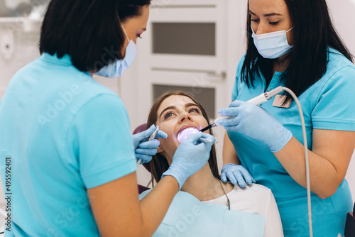 Dentists give the girl ultraviolet teeth whitening in a dental clinic