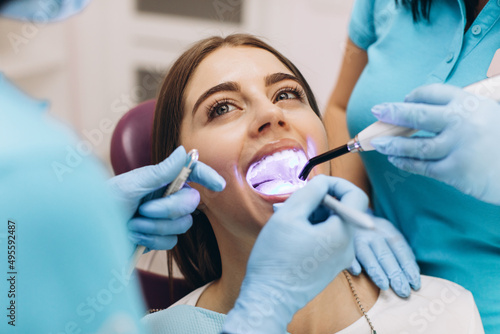 Dentists give the girl ultraviolet teeth whitening in a dental clinic