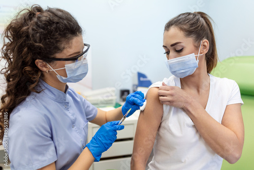 General practitioner vaccinating patient at hospital with copy space. Doctor giving injection to woman. Nurse holding syringe and using cotton before make Covid-19 or coronavirus vaccine.