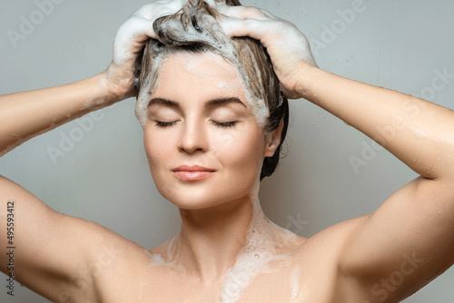 Young beautiful woman is washing her hair with a shampoo