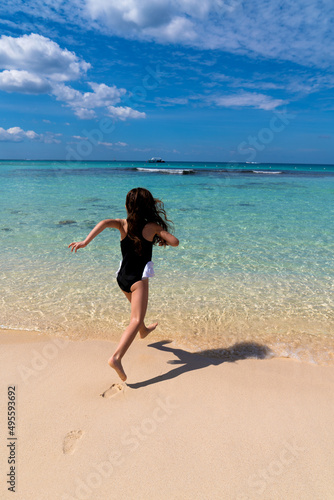 A little 6-year-old girl in a bathing suit runs towards the sea. The concept of travel and paradise holidays with children