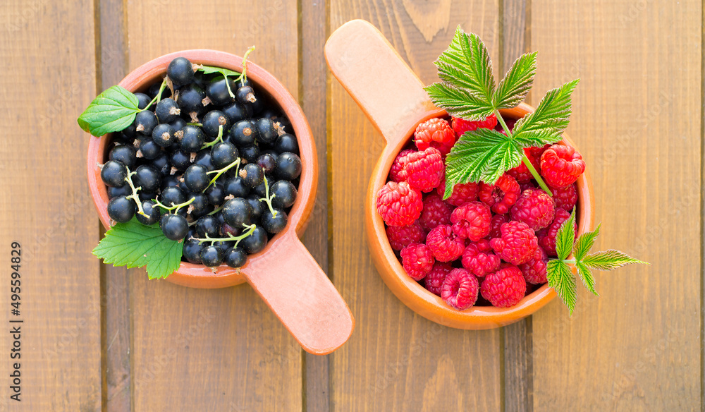 Two ceramic containers with raspberries and black currants