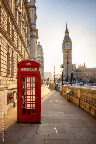 A classic  red telephone booth in front of the Big Ben clocktower in London  Westminster  during golden sunrise without people