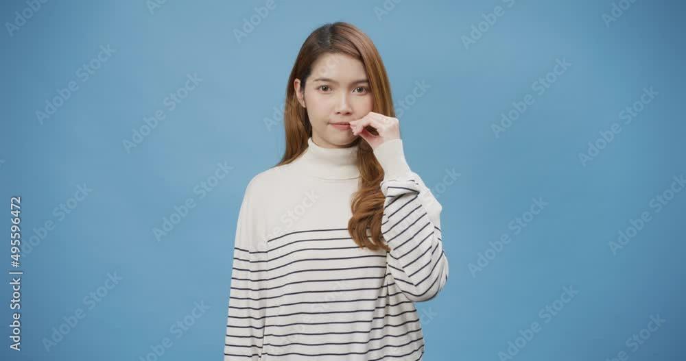 Youth attractive Asia lady with sweater close her mouth with hand like on zipper stand isolate on blue background. Can keep secret my lips are sealed, Female shut mouth, swear not tell anyone. Youth attractive Asia lady with sweater close her mouth with hand like on zipper stand isolate on blue background. Can keep secret my lips are sealed, Female shut mouth, swear not tell anyone.