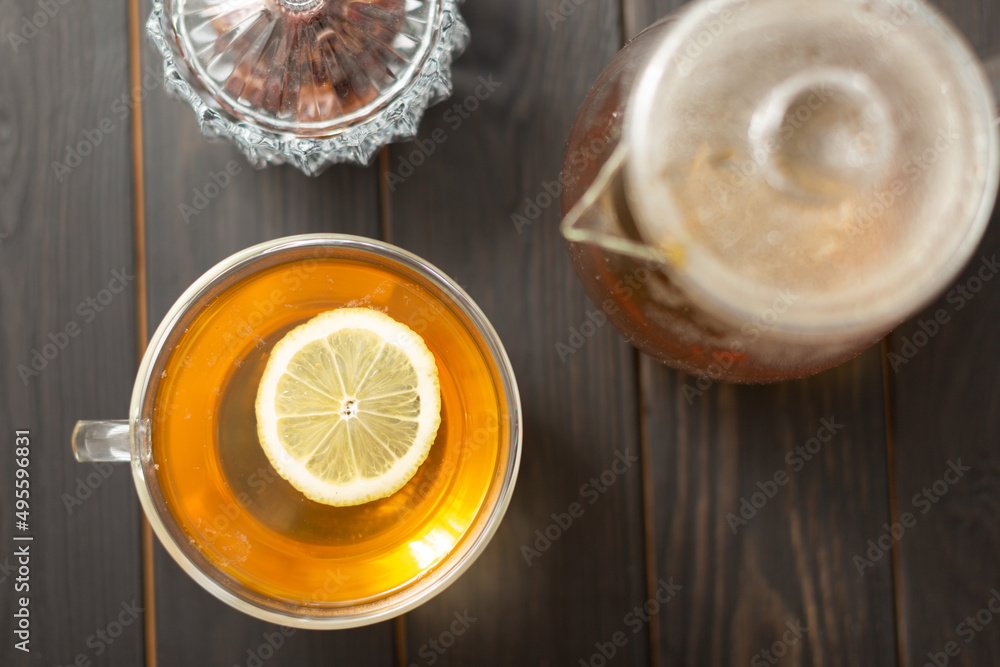 On a wooden table there is a teapot with freshly brewed natural green tea, a double-walled glass mug with tea and a slice of lemon, top view, flat lay On a wooden table there is a teapot with freshly brewed natural green tea, a double-walled glass mug with tea and a slice of lemon, top view, flat lay