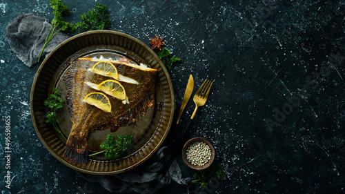 Fotografia Baked flounder fish with lemon and spices on a metal baking dish