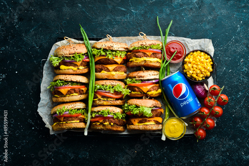 UKRAINE, LVIV - FEBRUARY 22, 2021: Pepsi cola bottle and hamburger with fresh vegetables, meat and cheese. Street food and drinks. Top view. Rustic style photo