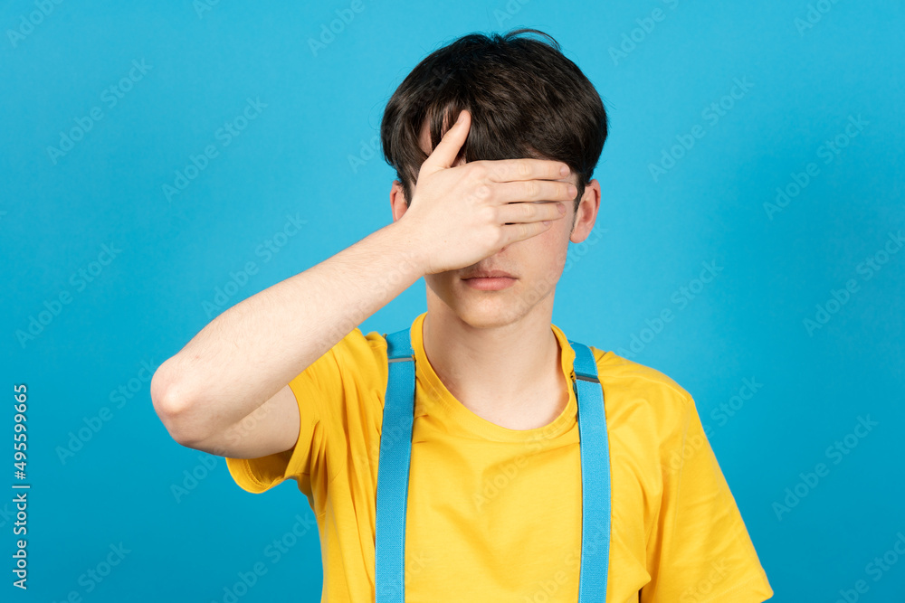 Teenager boy covering his eyes with hand. Anxiety and depression on adolescence concept Teenager boy covering his eyes with hand. Anxiety and depression on adolescence concept
