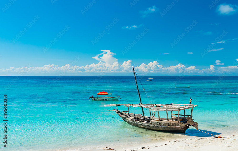 Wooden fishing ship on the white sand beach on low tide, Indian ocean. Zanzibar, Tanzania Wooden fishing ship on the white sand beach on low tide, Indian ocean. Zanzibar, Tanzania