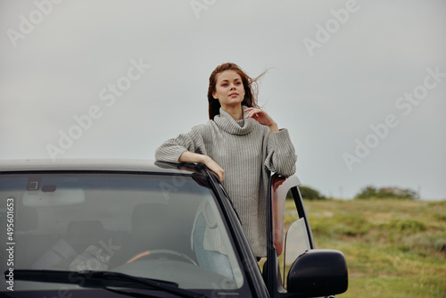 portrait of a woman with red hair in a sweater near the car nature Lifestyle