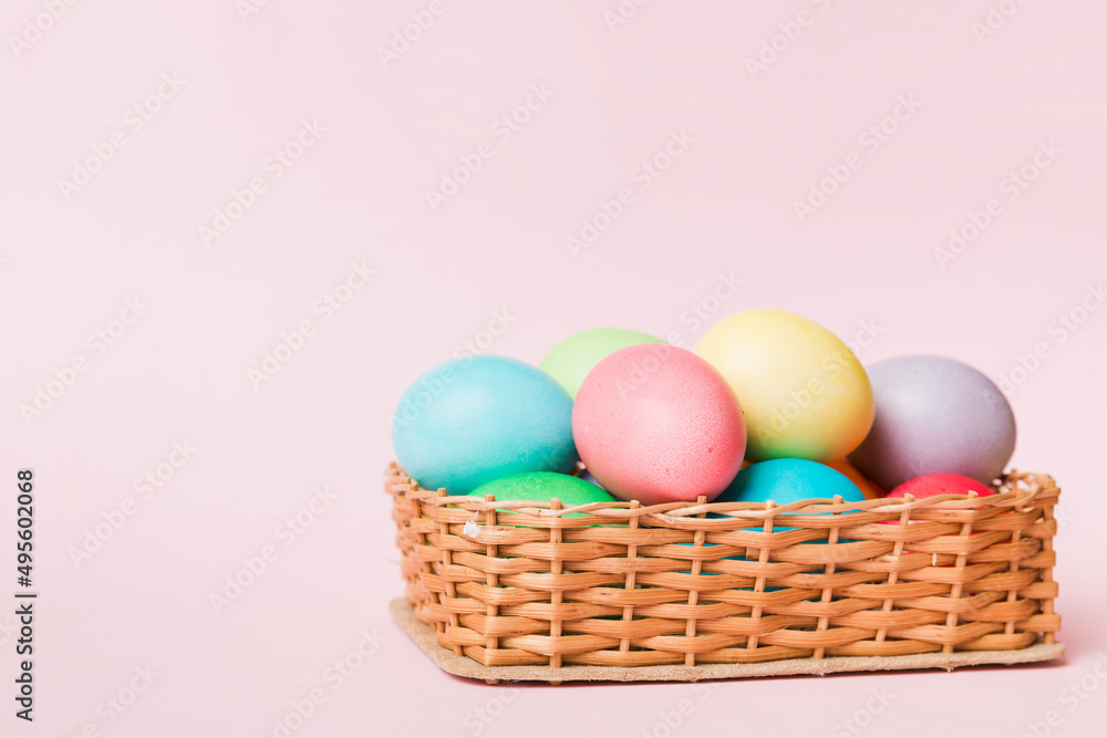 Multi colors Easter eggs in the woven basket on colored background . Pastel color Easter eggs. holiday concept with copy space Multi colors Easter eggs in the woven basket on colored background . Pastel color Easter eggs. holiday concept with copy space