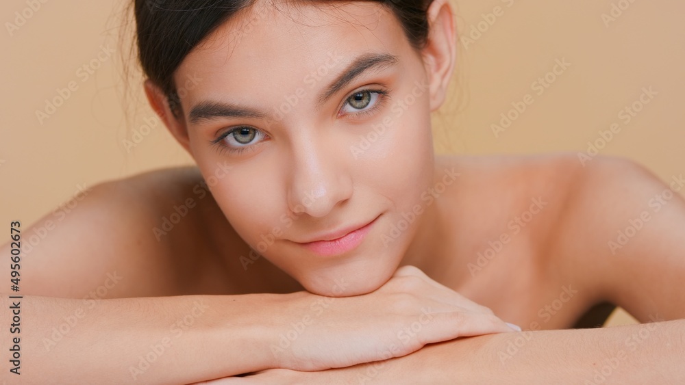 Beauty portrait of young brown-haired woman with perfect skin, who puts her chin down on her forearms, looks at camera and smiles | Skin care and beauty product promotional concept Beauty portrait of young brown-haired woman with perfect skin, who puts her chin down on her forearms, looks at camera and smiles | Skin care and beauty product promotional concept