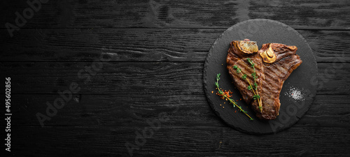 Aged Beef T-Bone steak. Juicy cooked steak with rosemary and spices. Top view. Rustic style. Flat Lay. photo