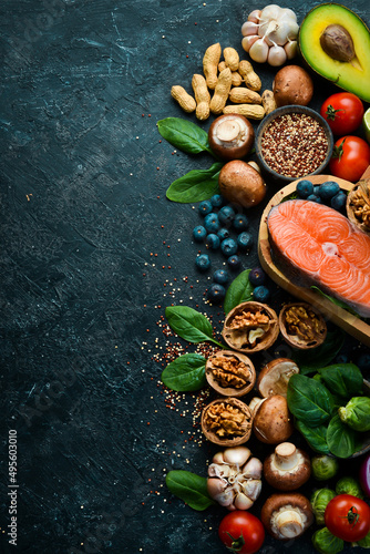 Heart health foods: salmon, avocados, blueberries, broccoli, nuts and mushrooms. On a black stone background. Top view. Copy space.