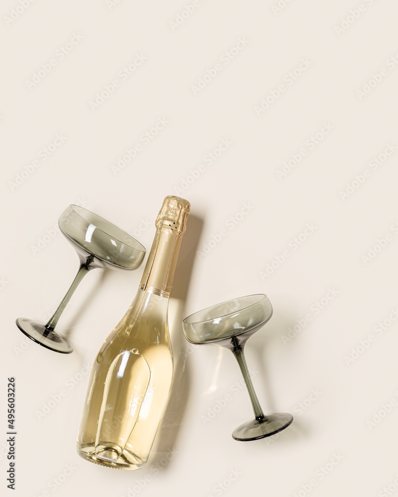 Champagne or sparkling wine bottle, champagne glasses from tinted grey glass on beige background. Festive drink minimal concept. Modern wine glasses, dark colored glass. Creative top view, flat lay Champagne or sparkling wine bottle, champagne glasses from tinted grey glass on beige background. Festive drink minimal concept. Modern wine glasses, dark colored glass. Creative top view, flat lay