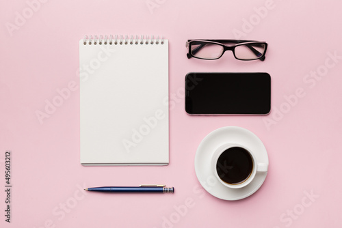Modern office desk table with notebook, smartphone and other supplies with cup of coffee. Blank notebook page for you design. Top view, flat lay