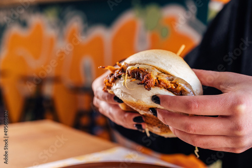 Pulled pork burger in someone's hands, lanch time at the restaurant. photo