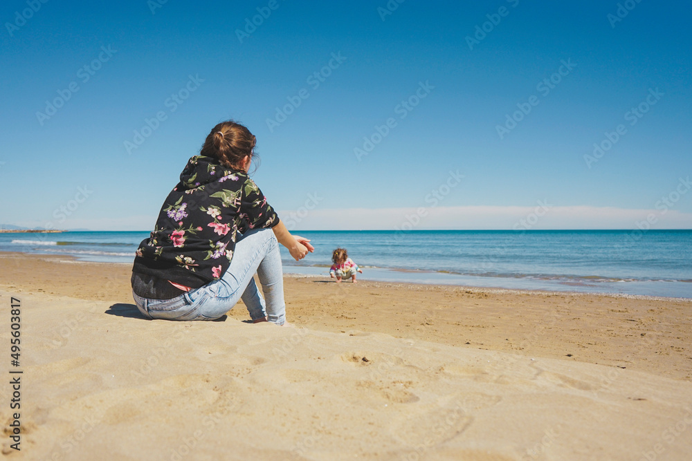 Young single mom caring her little girl at the beach