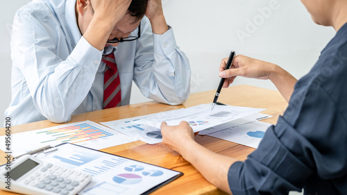 Male employee is holding his head with feeling stress about unsuccessful project after executive checking