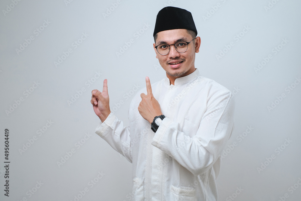 Asian muslim mas pointing something on his side with his both hand Asian muslim mas pointing something on his side with his both hand