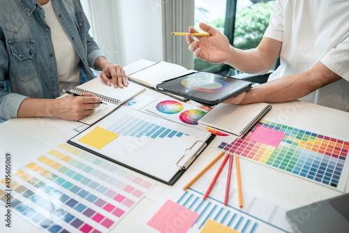 Two creative graphic designer working on color selection and drawing on graphics tablet at workplace, Color swatch samples chart