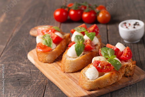 Italian tomato and cheese bruschetta. Tapas, antipasti with chopped vegetables, herbs and oil on grilled ciabatta and baguette bread.